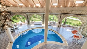 Ein hallenbad mit gebogenem Design, Steinwänden und Blick auf einen Garten.