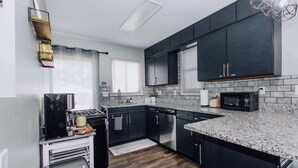 A modern kitchen with dark cabinets, a granite countertop, a built-in microwave, and a gas stove.