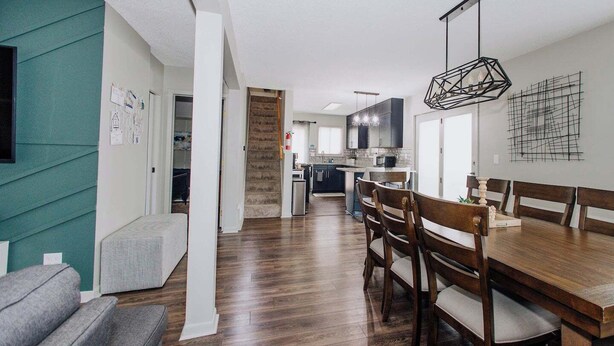 A modern kitchen with dark countertops, a central island, and a hanging light fixture.