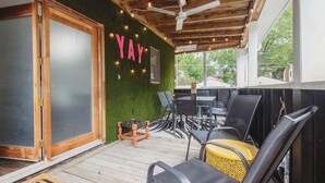 A covered outdoor seating area with chairs and tables, a wooden ceiling, and a green wall with a 'YAY' sign.