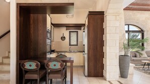 Una cocina moderna con armarios de madera oscura, una zona de comedor con dos sillas y una pared de piedra.