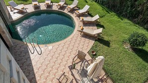Una piscina circular con solárium empinado, rodeada de sillas de descanso y una pequeña mesa.