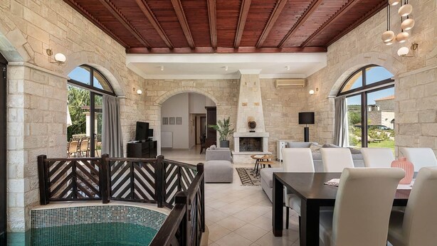 Amplia sala de estar con chimenea de piedra, piscina y zona de comedor con asientos exteriores.