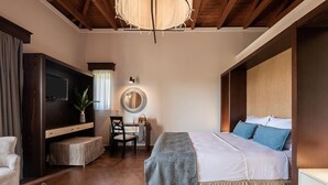 Un dormitorio con cama, escritorio, silla, televisor y un espejo grande.
