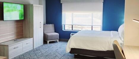 Habitación de hotel con cama, escritorio, silla, televisor y ventana.