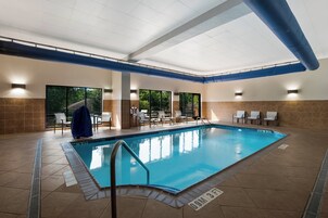 Una piscina interior con agua cristalina, rodeada de paredes de azulejos y un techo con tuberías azules.