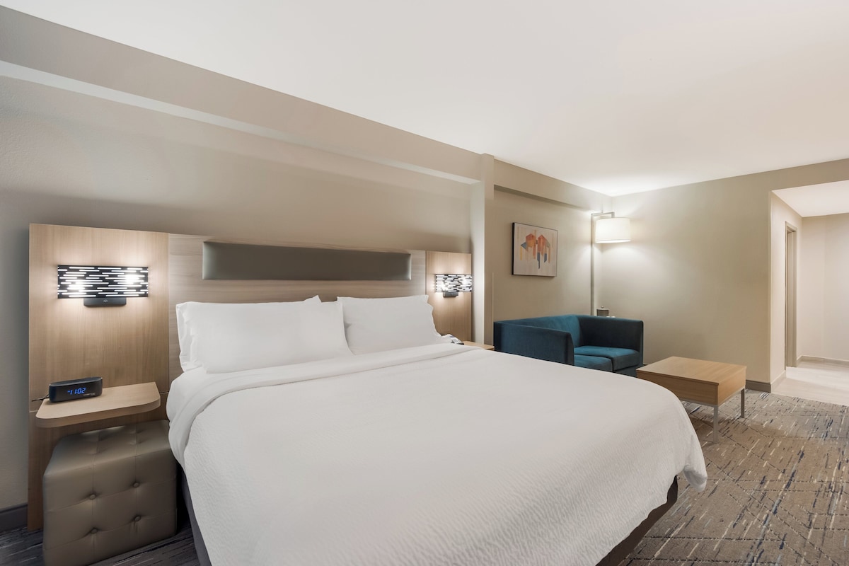 A hotel room with a large bed, bedside tables, a desk, and a chair.