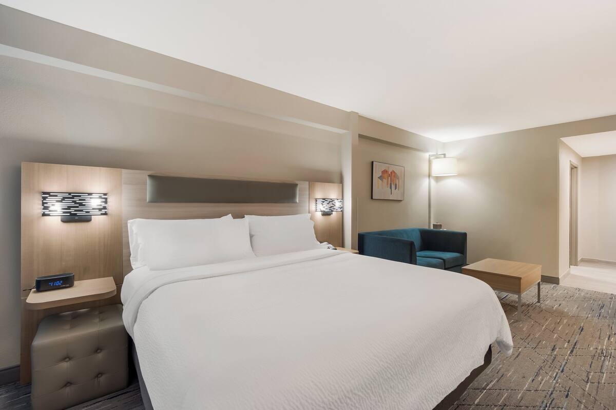 A hotel room with a large bed, bedside tables, a desk, and a chair.