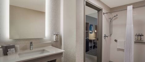 A modern bathroom with a large mirror, a sink, and a shower area.