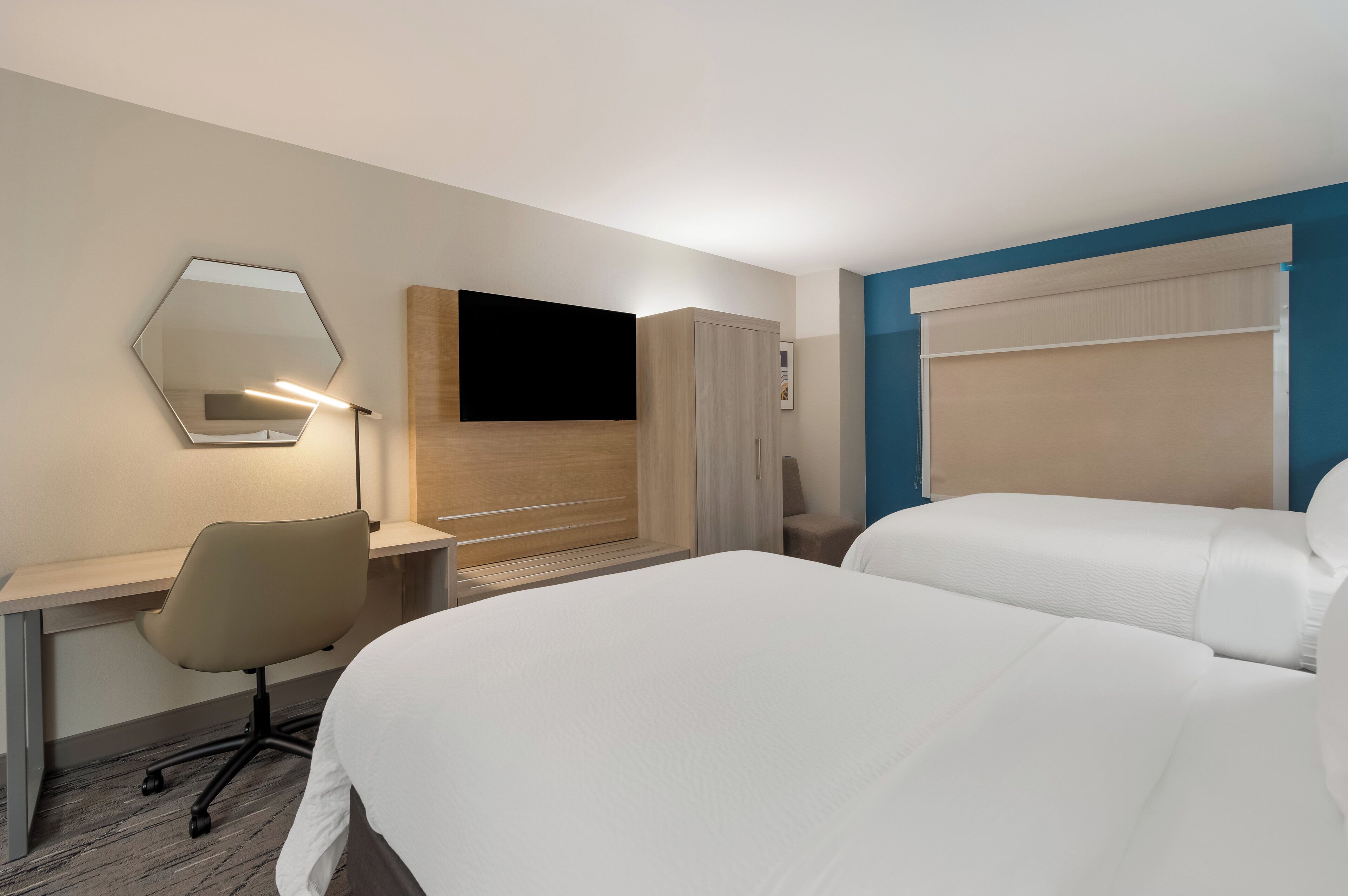 Een hotelkamer met een bed, een bureau met stoel, een televisie en een kledingkast.