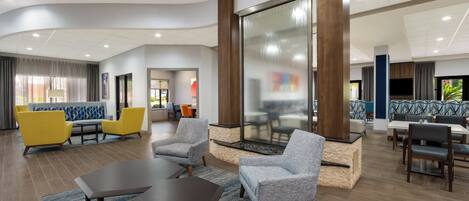A modern lobby with seating areas, a fireplace, and a large glass wall.