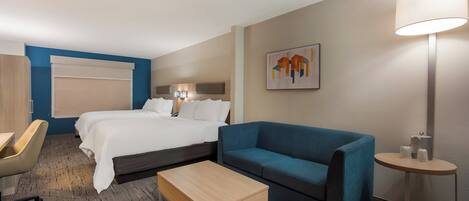 Une chambre d’hôtel avec un lit, un canapé bleu, une table basse en bois, un bureau et une lampe.
