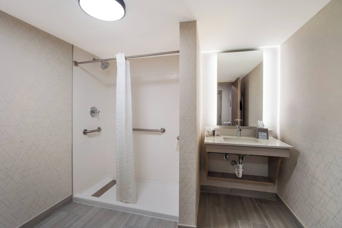 A modern bathroom with a glass-enclosed shower, a vanity with a mirror, and a sink.