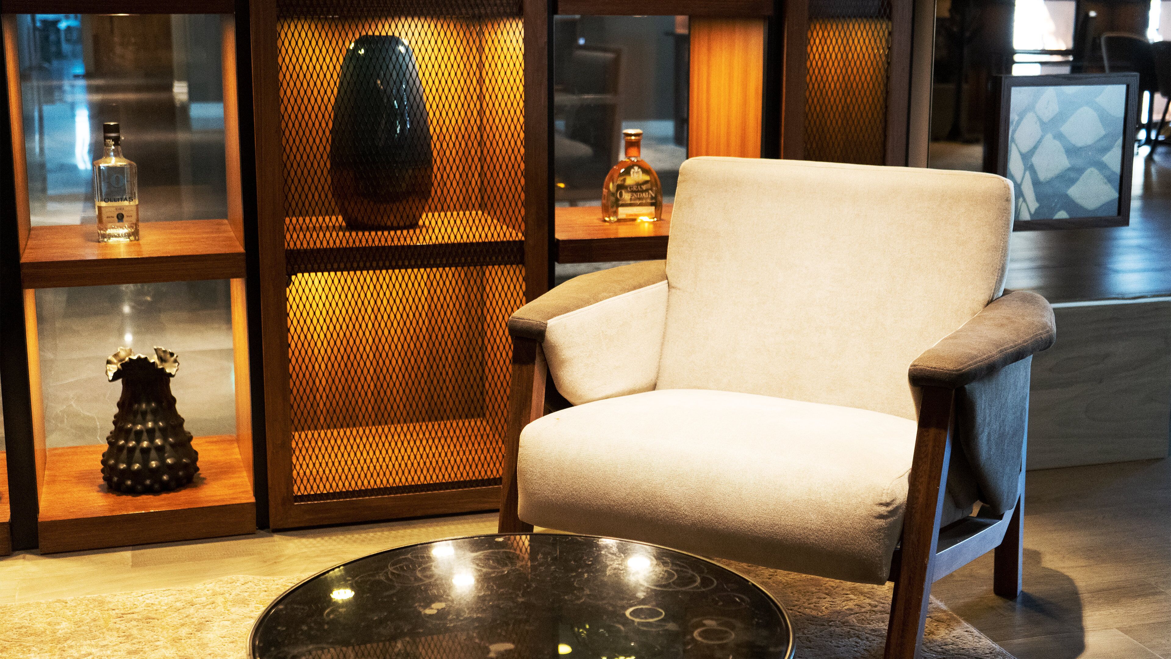 A modern armchair in a well-lit room with a glass partition displaying various items.