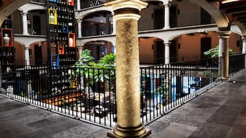 Un atrio amplio con una columna central, rodeado por una cerca de hierro forjado negro.