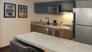 Una cocina moderna con encimeras de granito, electrodomésticos de acero inoxidable y armarios de madera.