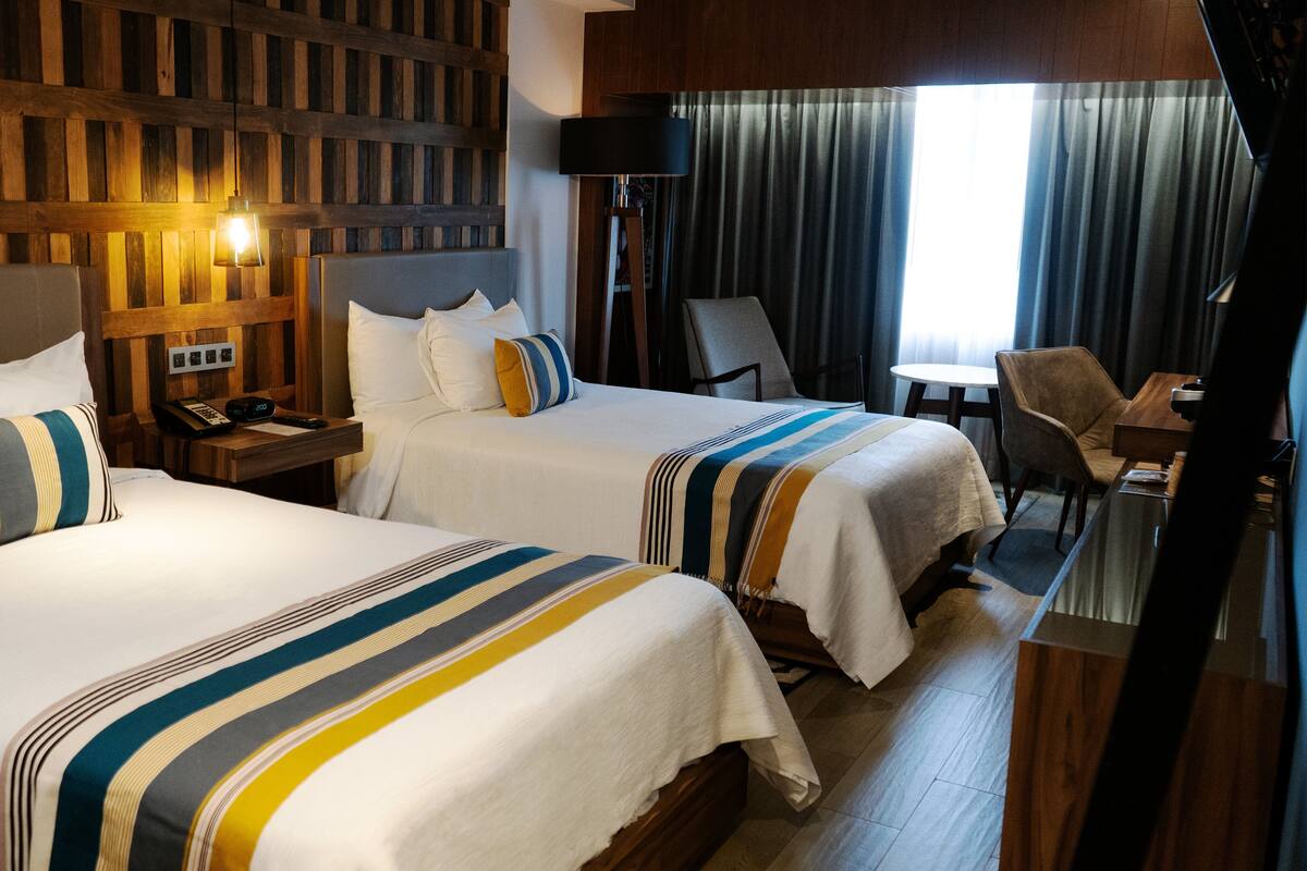 Een hotelkamer met twee bedden, een bureau en een stoel.