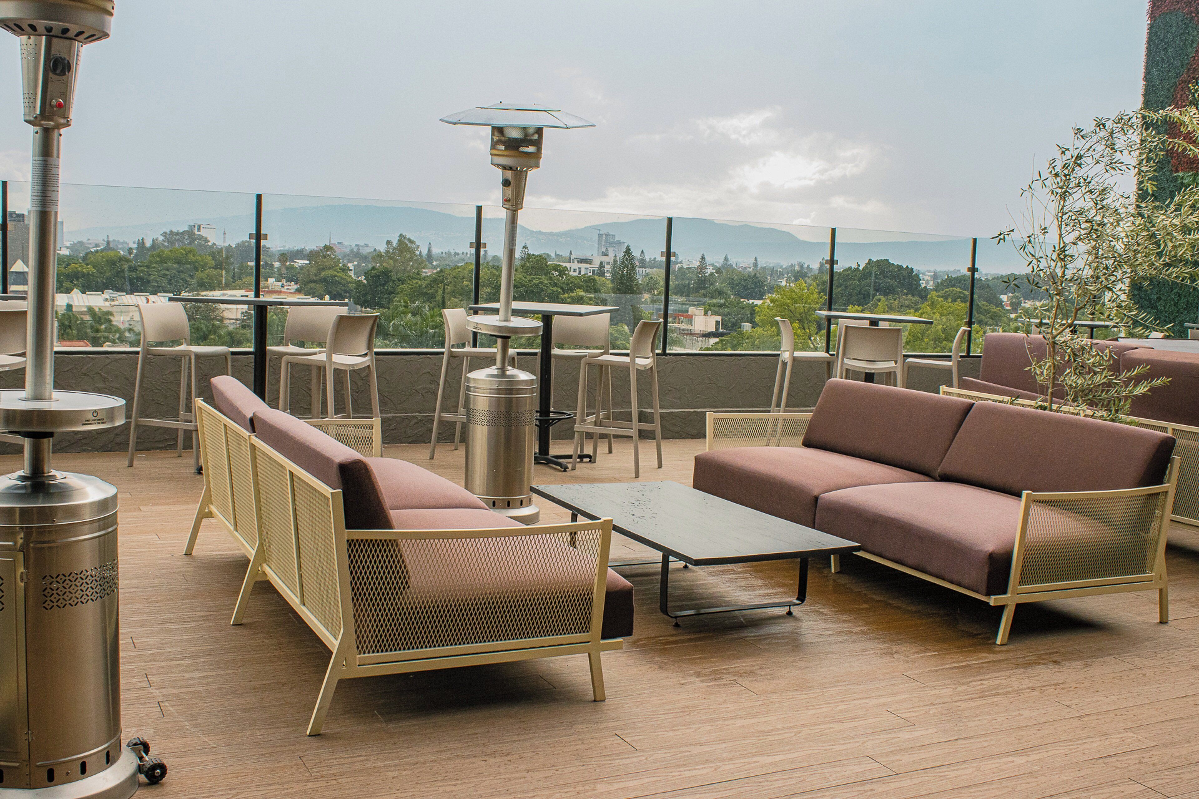 A rooftop terrace with outdoor seating, including sofas and chairs, and a table.