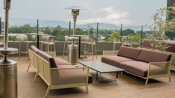 A rooftop terrace with outdoor seating, including sofas and chairs, and a table.