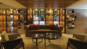 A cozy living room with a sectional sofa, two round coffee tables, and a brick accent wall.