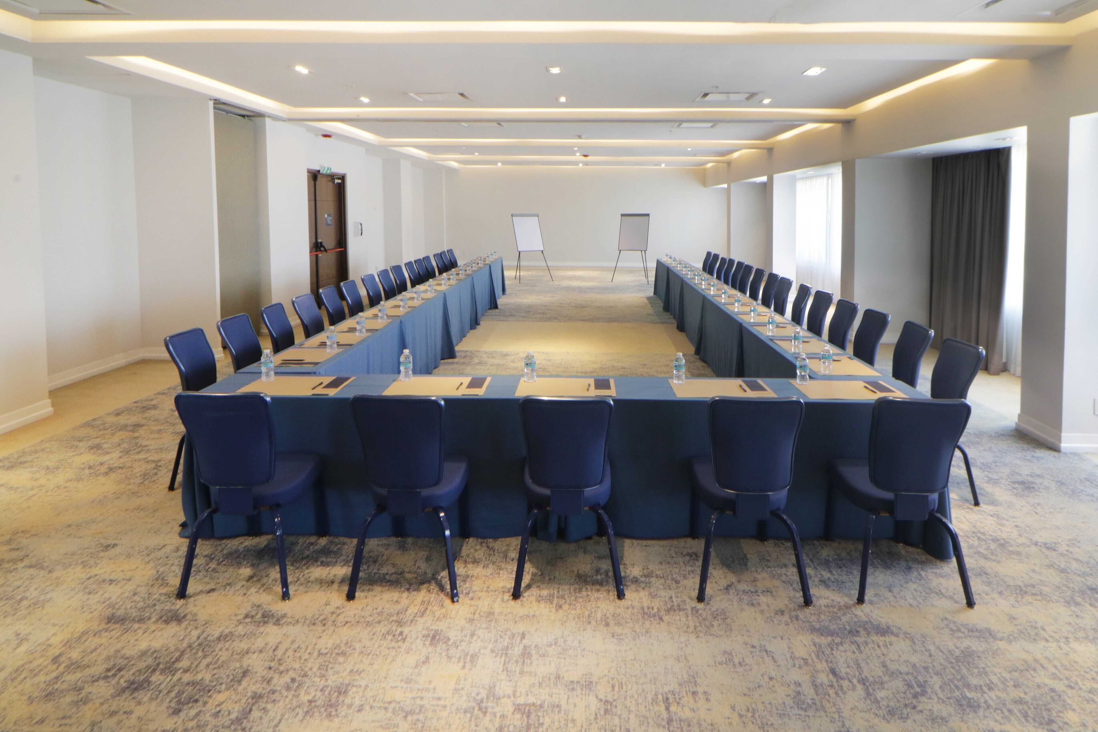 Una sala conferenze con un lungo tavolo, sedie, una lavagna e un pavimento rivestito di moquette.