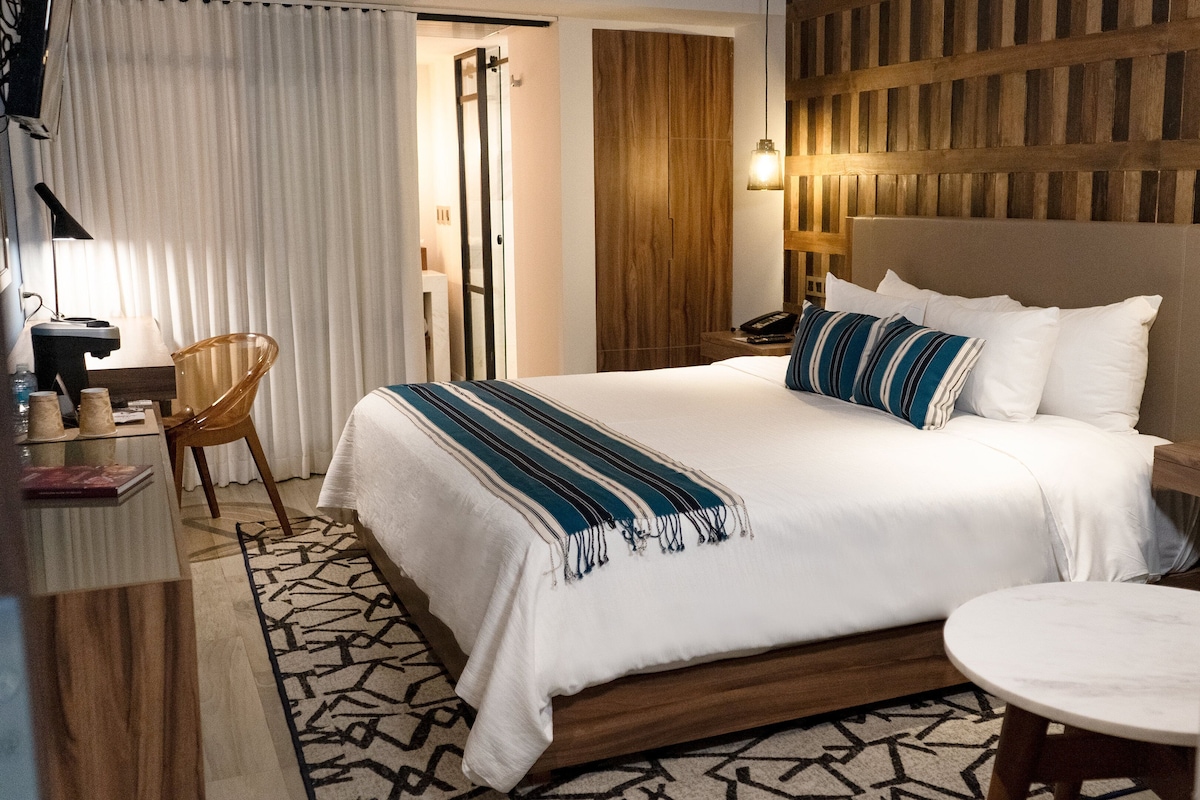 Une chambre d’hôtel comprenant un lit, un bureau, une chaise, une table de chevet et une petite table ronde.