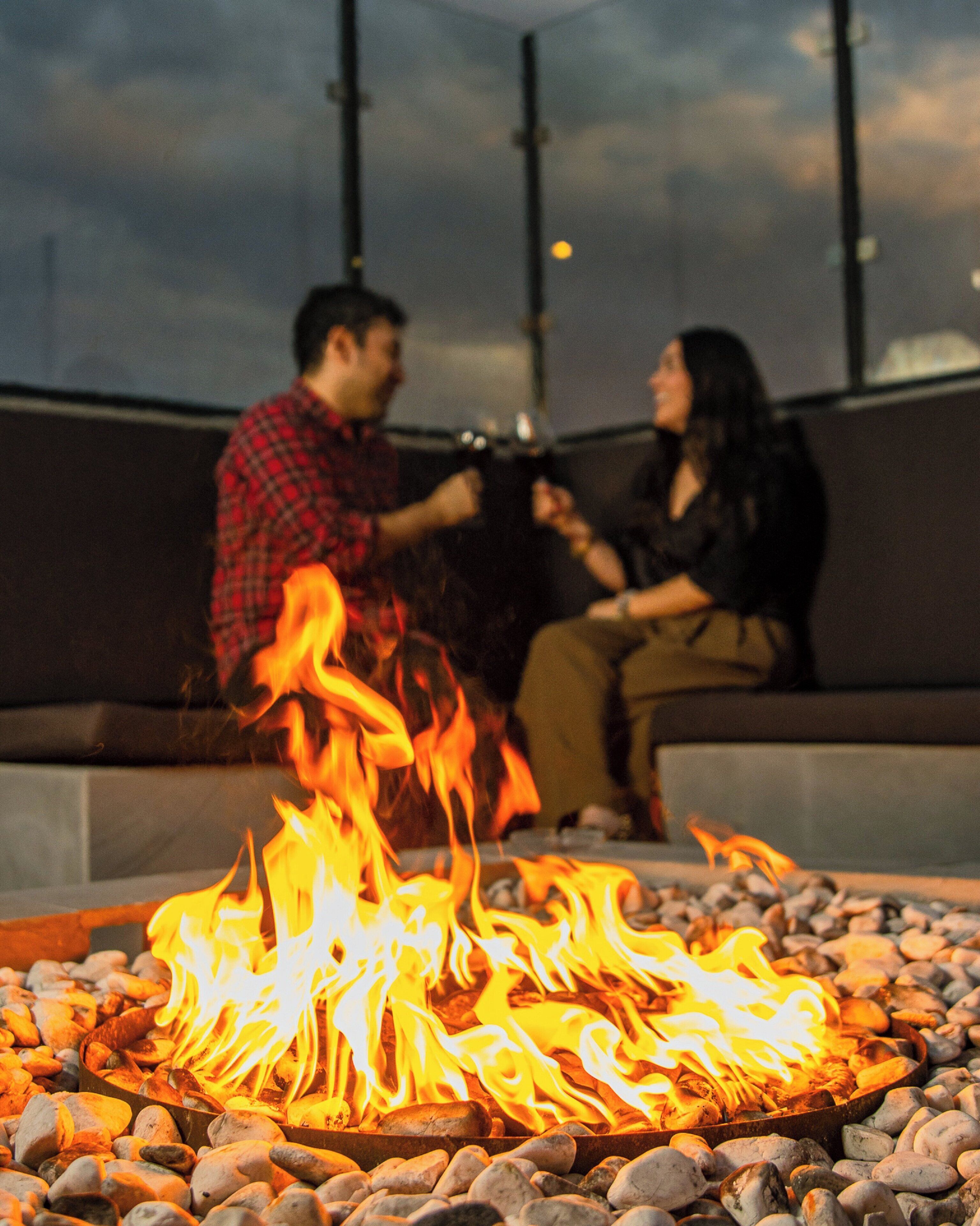 A couple sitting by a fire pit with a modern outdoor setting.