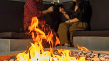 A couple sitting by a fire pit with a modern outdoor setting.