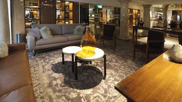 A modern lounge area with a sofa, two round tables, and a wooden coffee table.