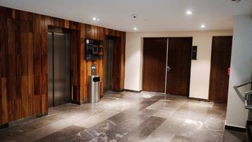 A modern elevator area with wooden paneling and a marble floor.