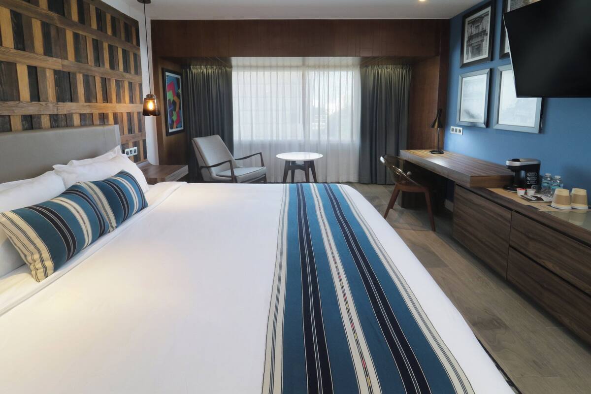 Een hotelkamer met een groot bed, een bureau, een stoel en een klein rond tafeltje.