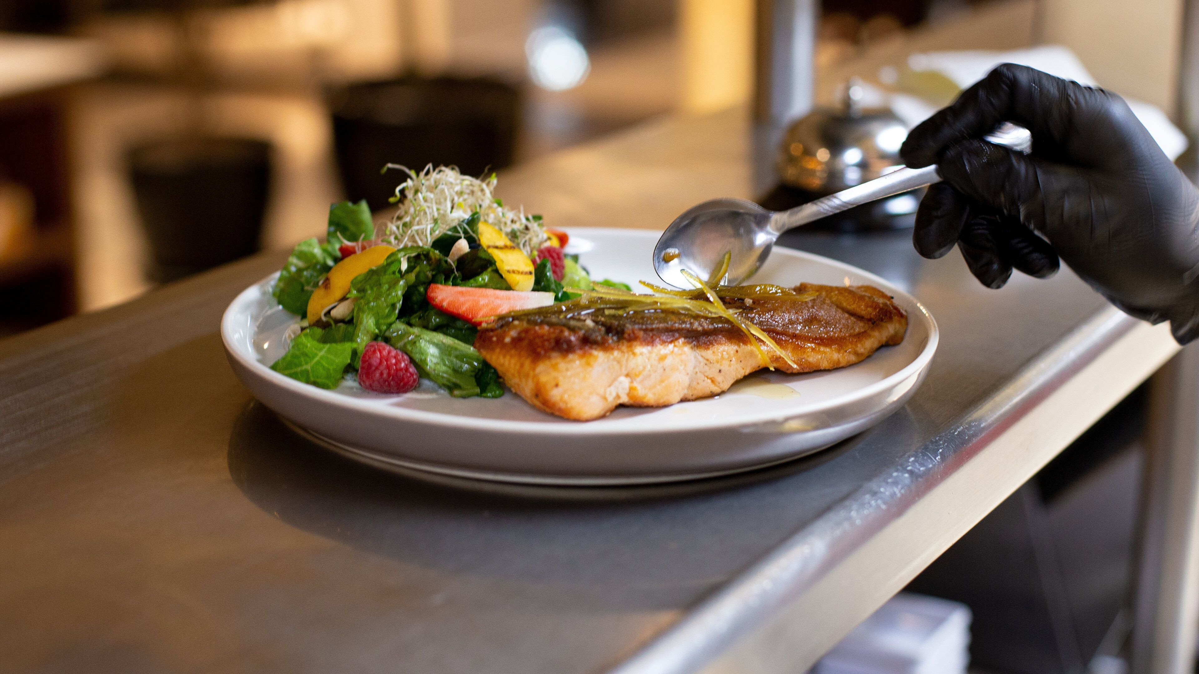 Une assiette contenant un poisson grillé, une salade et une cuillère.