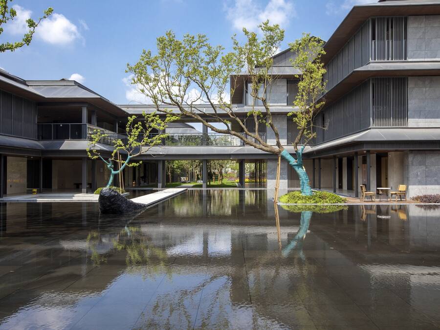 A modern building with a reflective water feature in the courtyard.