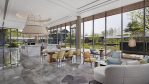 Un interior espacioso y moderno con un amplio comedor, asientos confortables y grandes ventanales que ofrecen vistas al exterior.