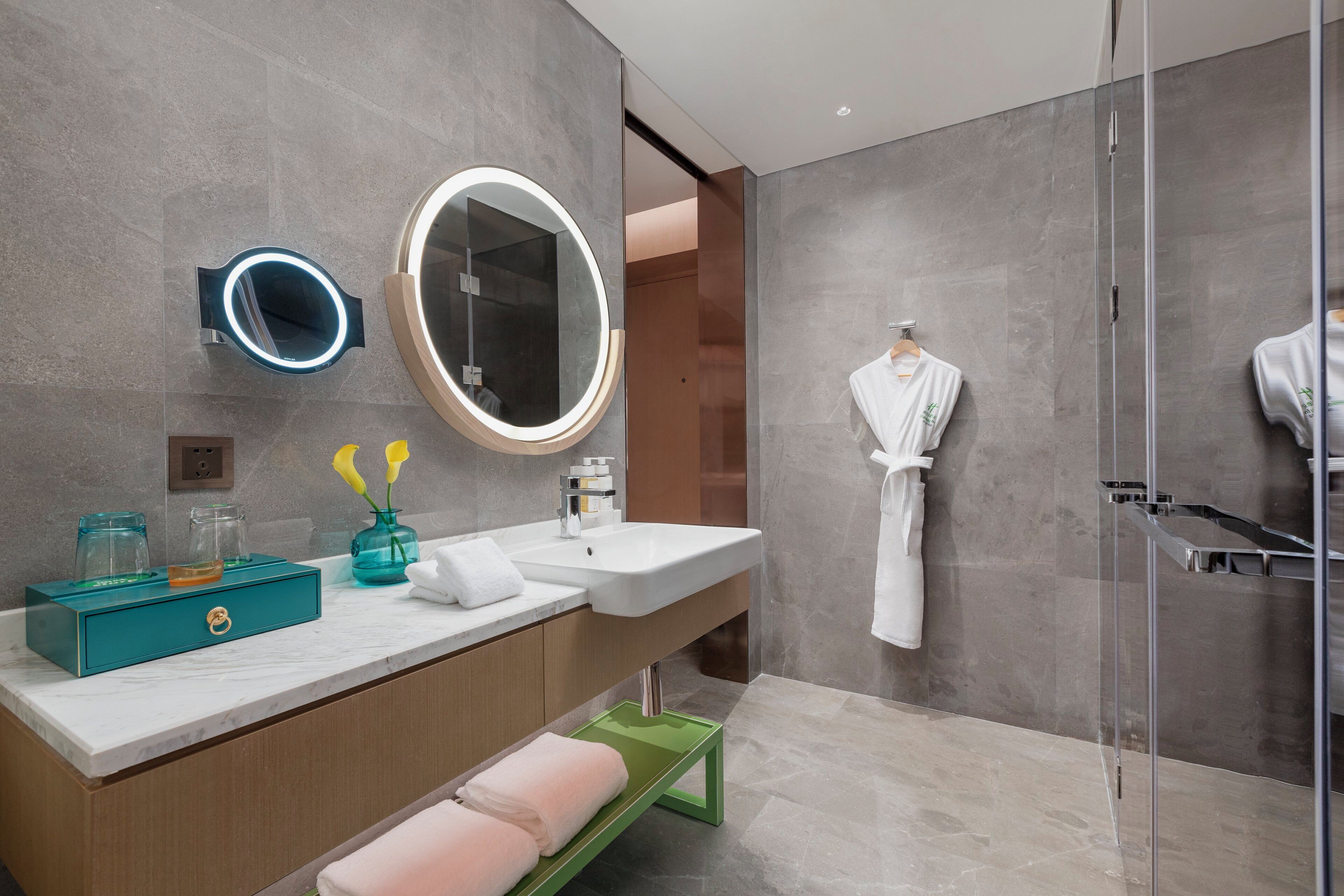 A modern bathroom with a large mirror, a vanity with a sink, and a glass shower enclosure.