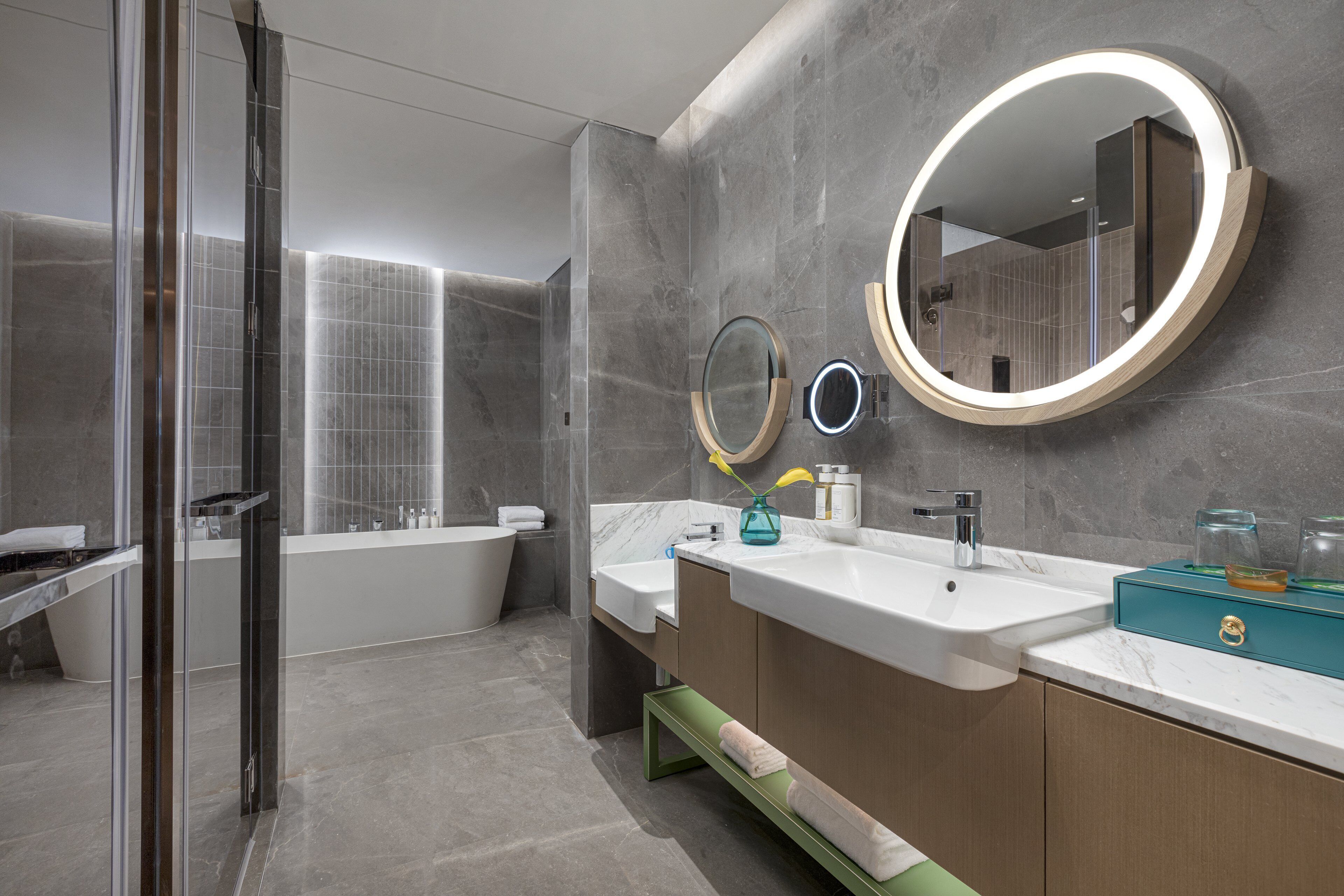 Un baño moderno con cabina de ducha de vidrio, una bañera independiente y un tocador con lavamanos dobles y un espejo grande.