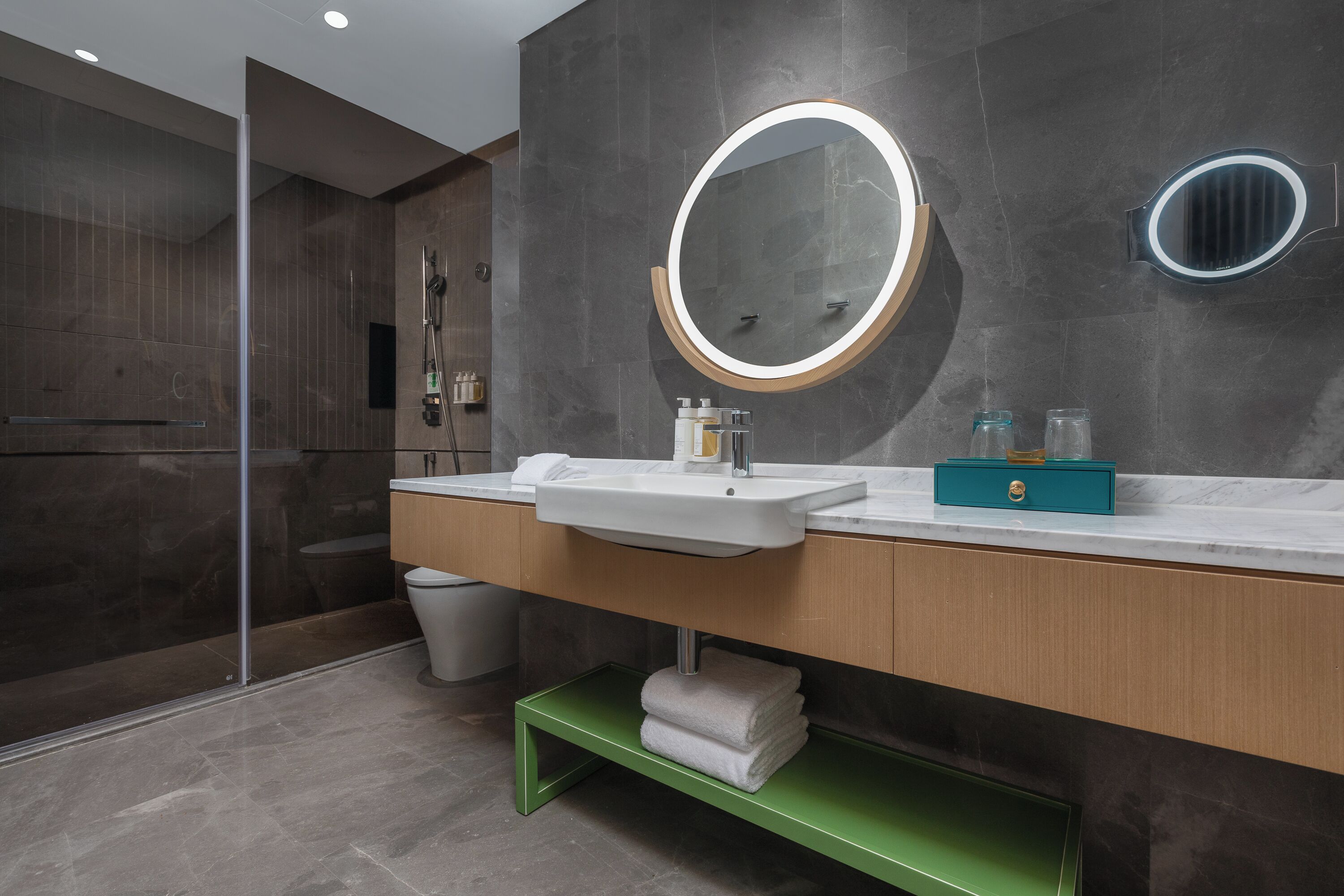 Een moderne badkamer met een grote spiegel, twee wastafels en een douchegedeelte.