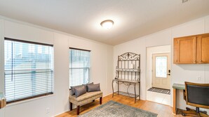 A room with a wooden floor, a bench with cushions, a patterned rug, a metal shelf unit, and a desk with a chair. - Pet-Friendly St Augustine Home w/ Dock & Yard! (St. Augustine)