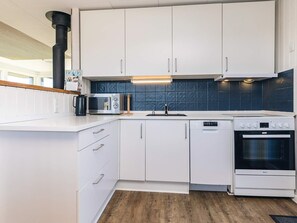 A modern kitchen with white cabinetry, a built-in microwave, a stove, and a dishwasher. - 4 Star Holiday Home in Hjorring (Hjørring)
