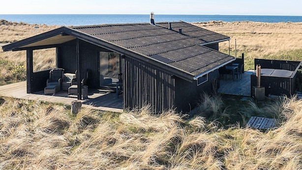 A beach house with a deck, outdoor seating, and a view of the ocean. - 4 Star Holiday Home in Hjorring (Hjørring)