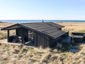 Une maison de plage avec une terrasse, un espace salon extérieur et une vue sur l’océan.
