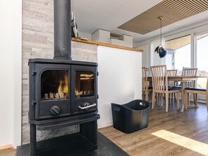 Ein modernes Interieur mit Kaminofen, Essbereich mit Holzsesseln und großem Fenster.