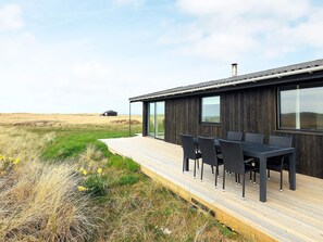 Une maison moderne dotée d’une terrasse, d’un espace salon extérieur et offrant une vue sur le paysage.