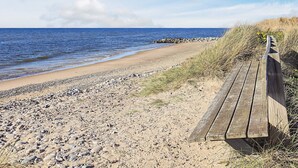 A beach with a wooden walkway, pebbles, and a rocky shoreline. - 4 Star Holiday Home in Hjorring (Hjørring)