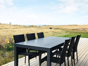 A deck with a table and chairs overlooking a grassy landscape. - 4 Star Holiday Home in Hjorring (Hjørring)