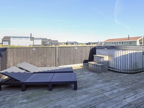 A wooden deck with a lounge chair and a hot tub.
