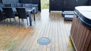 A wooden deck with outdoor seating and a hot tub.