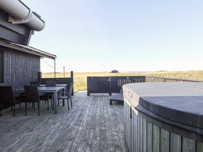A wooden deck with a hot tub, a table with chairs, and a view of the landscape. - 4 Star Holiday Home in Hjorring (Hjørring)