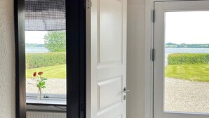 Une porte blanche donnant sur un lac et une végétation luxuriante.