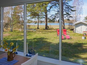 A room with a large window overlooking a grassy yard with trees and a shed.